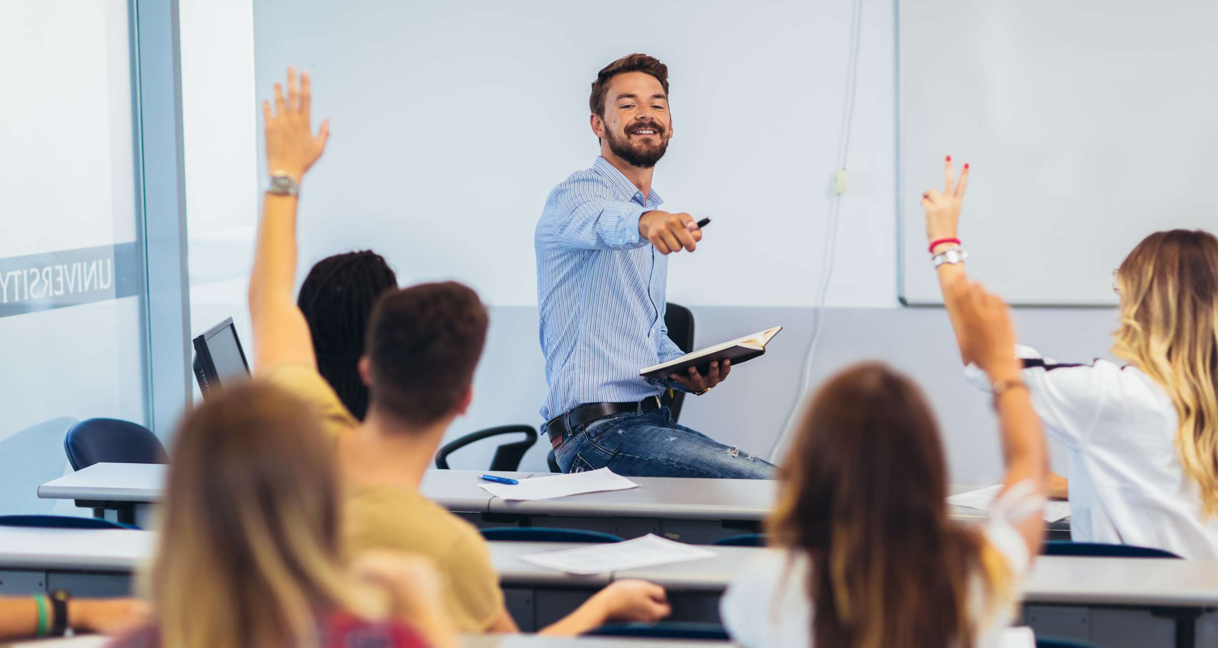 Group of students raising hands in class on lecture.